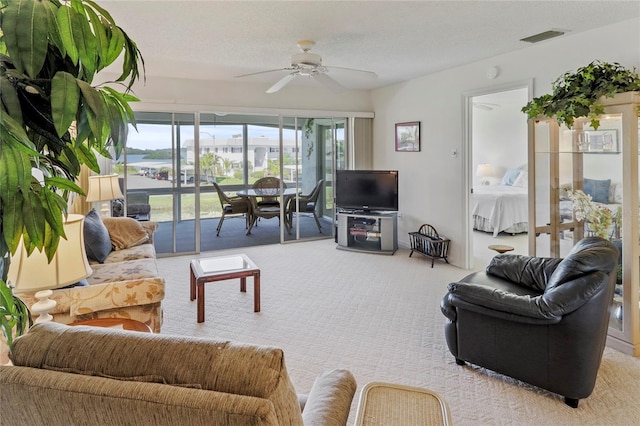 carpeted living area with ceiling fan, a textured ceiling, and visible vents