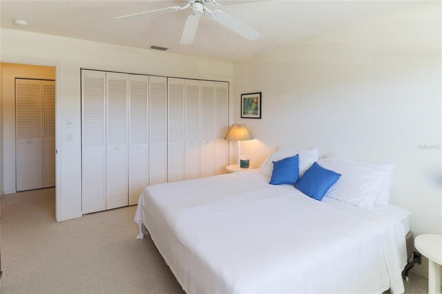 carpeted bedroom featuring ceiling fan, visible vents, and a closet