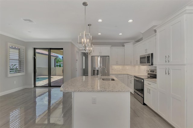 kitchen with a center island with sink, light stone countertops, appliances with stainless steel finishes, and white cabinetry