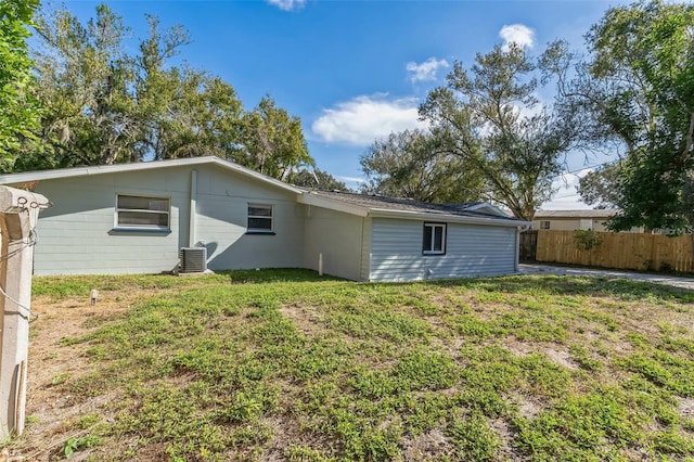 back of property featuring a lawn and central air condition unit