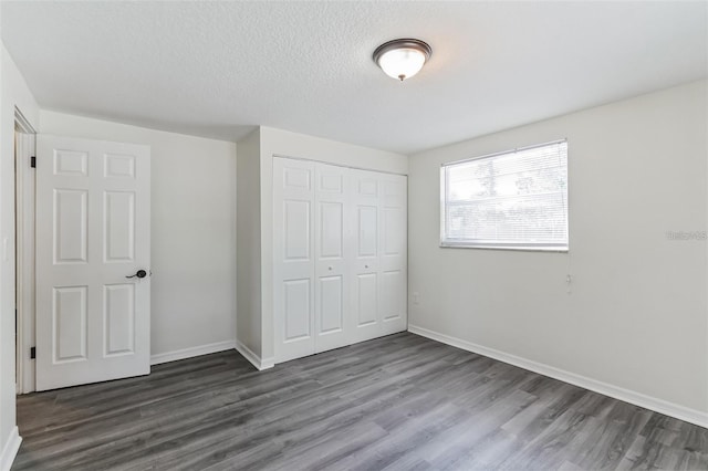 unfurnished bedroom with a closet, dark hardwood / wood-style flooring, and a textured ceiling