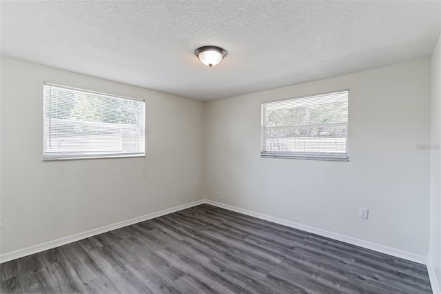 spare room with a textured ceiling, dark wood-style flooring, and baseboards