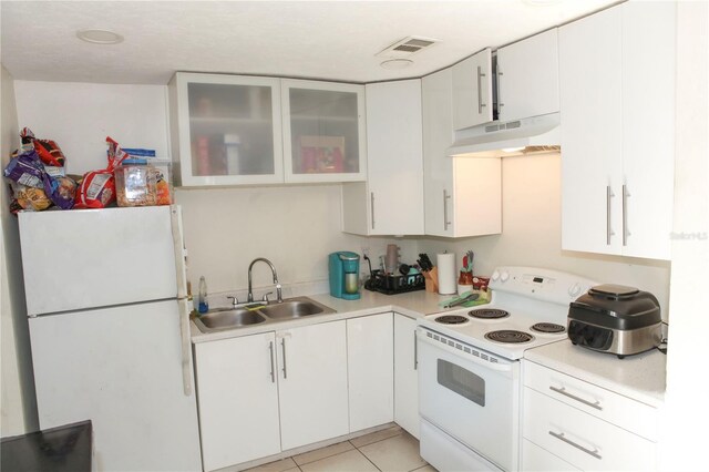 kitchen with light tile patterned floors, white appliances, sink, and white cabinets