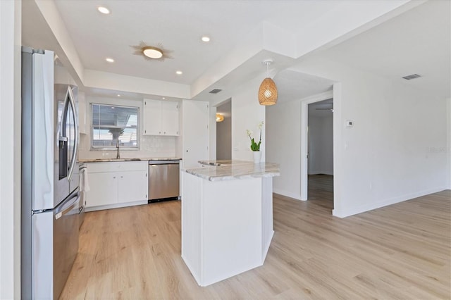 kitchen featuring light stone countertops, light hardwood / wood-style flooring, stainless steel appliances, decorative backsplash, and white cabinetry