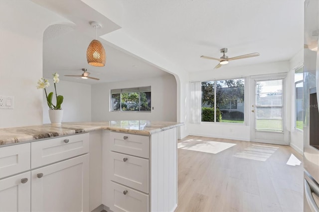 kitchen featuring light stone countertops, light hardwood / wood-style floors, hanging light fixtures, ceiling fan, and white cabinets