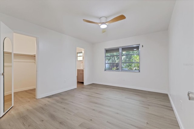 unfurnished bedroom featuring a closet, ceiling fan, a spacious closet, and light hardwood / wood-style flooring