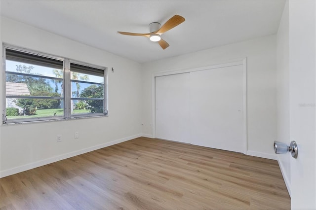 unfurnished bedroom featuring ceiling fan, a closet, and light wood-type flooring