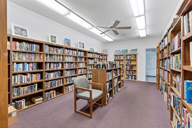 living area with a textured ceiling, ceiling fan, and carpet