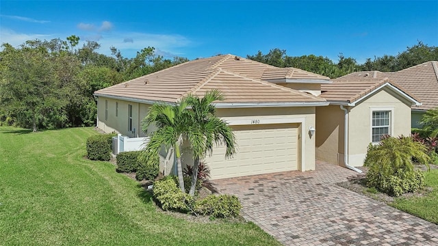 view of front of home with decorative driveway, a tile roof, stucco siding, a garage, and a front lawn