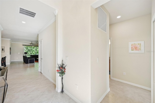 hall featuring visible vents, crown molding, baseboards, and light tile patterned floors