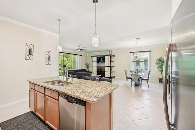 kitchen with an island with sink, appliances with stainless steel finishes, light stone counters, crown molding, and a sink