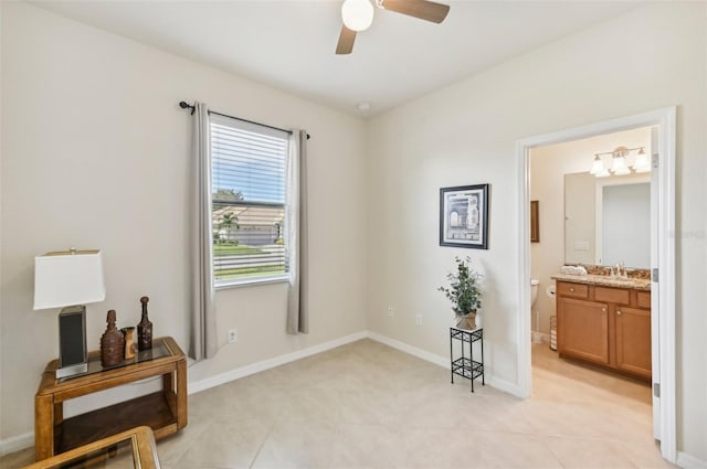 interior space with ensuite bathroom, light tile patterned flooring, a ceiling fan, and baseboards