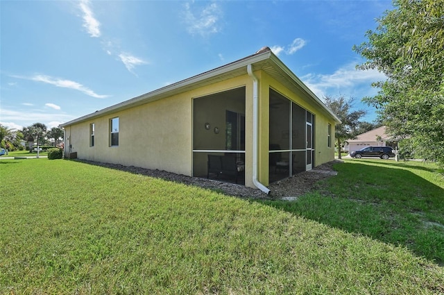 view of property exterior featuring a lawn, a sunroom, and stucco siding