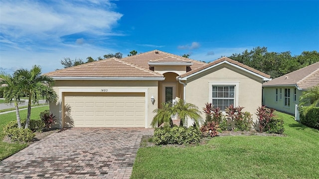 view of front of property with a tiled roof, an attached garage, decorative driveway, a front yard, and stucco siding