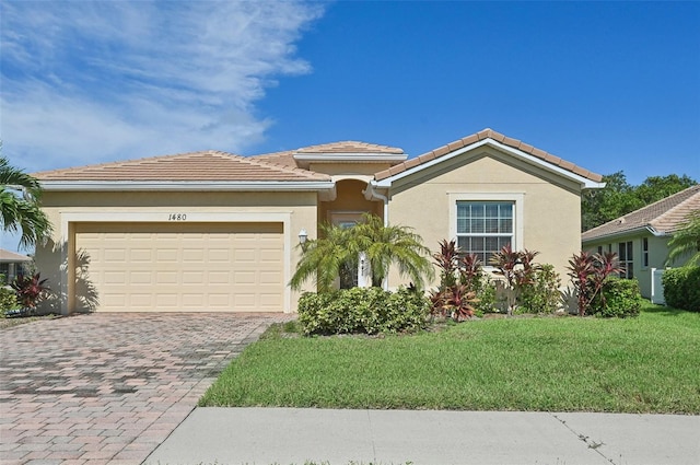 view of front of property featuring an attached garage, a tiled roof, decorative driveway, stucco siding, and a front lawn