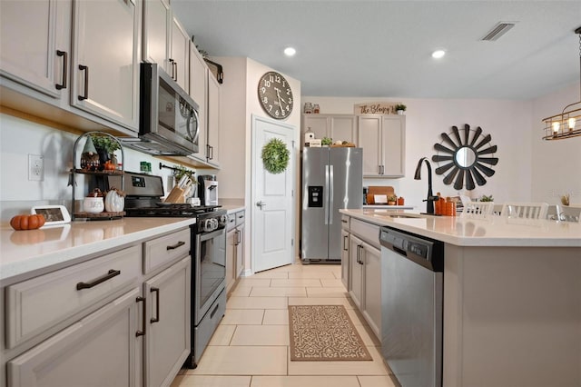 kitchen with gray cabinetry, sink, appliances with stainless steel finishes, decorative light fixtures, and light tile patterned flooring