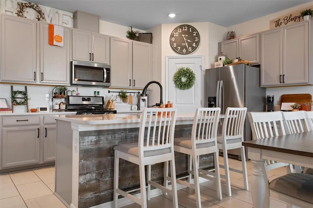 kitchen featuring light tile patterned floors, a center island, stainless steel appliances, and gray cabinets