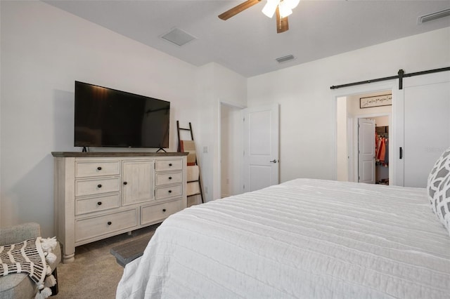 bedroom featuring a barn door, carpet floors, a spacious closet, and ceiling fan