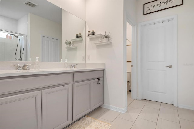 bathroom with a shower with door, vanity, and tile patterned flooring