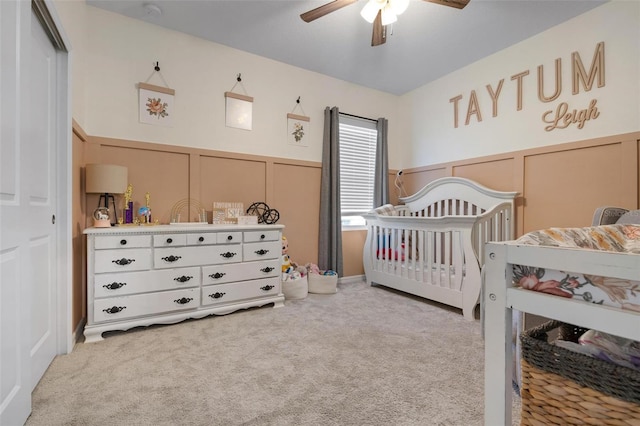 carpeted bedroom featuring ceiling fan, a closet, and a crib