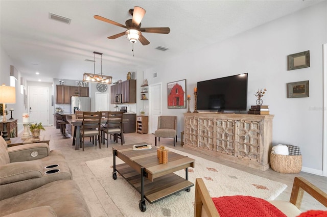 living room featuring ceiling fan with notable chandelier and light wood-type flooring