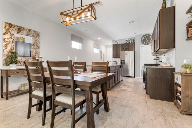 dining area with a textured ceiling and light hardwood / wood-style floors