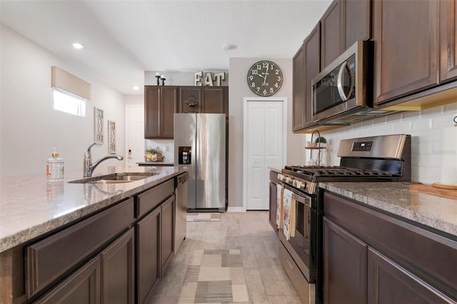 kitchen with stainless steel appliances, sink, light stone countertops, and decorative backsplash