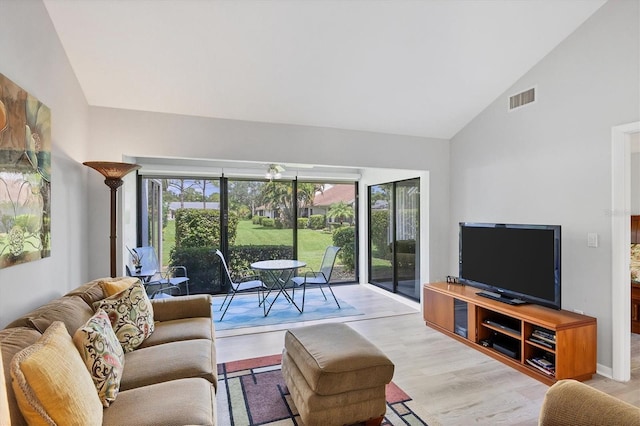 living area with light wood-style floors, visible vents, and high vaulted ceiling