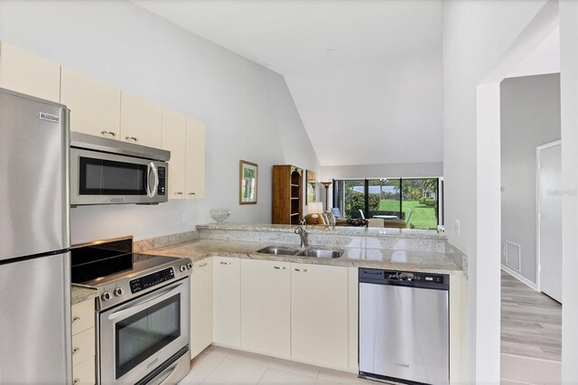 kitchen with cream cabinets, sink, light hardwood / wood-style floors, kitchen peninsula, and stainless steel appliances