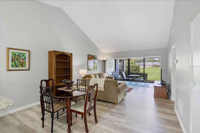 dining area featuring high vaulted ceiling and light wood-type flooring