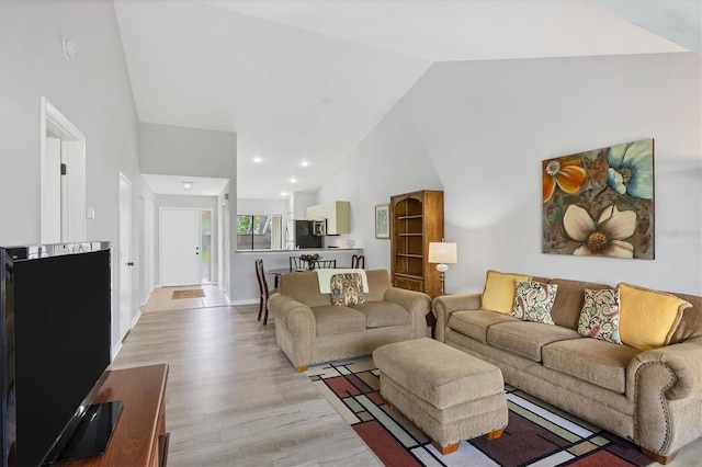 living room with recessed lighting, light wood-style floors, baseboards, and high vaulted ceiling