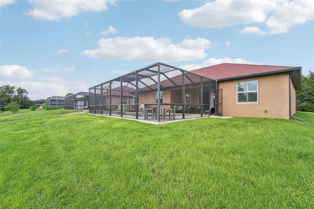 rear view of house with glass enclosure, a yard, and a patio