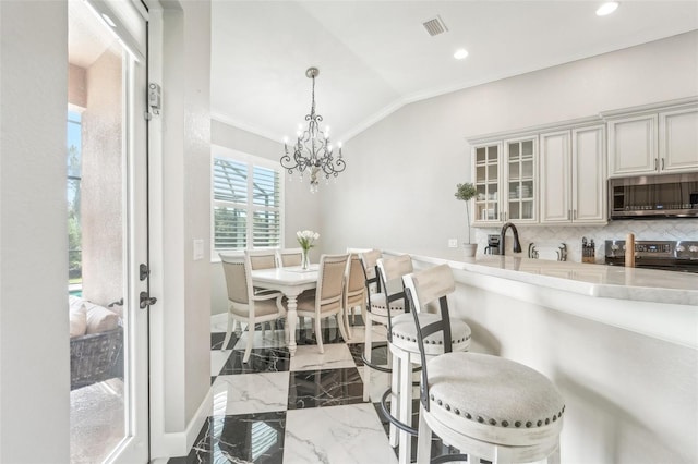 dining space with crown molding, sink, a chandelier, and lofted ceiling