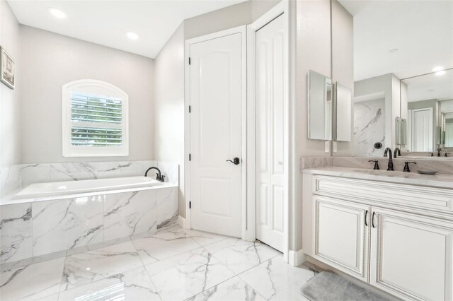 bathroom featuring vanity and a relaxing tiled tub