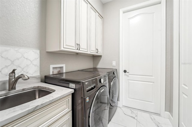 clothes washing area featuring cabinets, washer and dryer, and sink