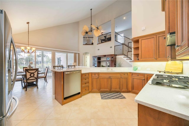 kitchen featuring decorative light fixtures, kitchen peninsula, stainless steel appliances, high vaulted ceiling, and a chandelier