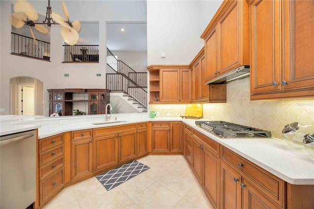 kitchen featuring appliances with stainless steel finishes, kitchen peninsula, sink, a towering ceiling, and light tile patterned flooring