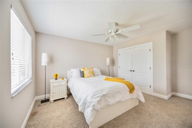 bedroom featuring light colored carpet, ceiling fan, and a closet