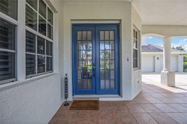 entrance to property with a garage, french doors, and a porch