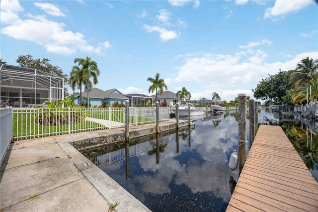 view of dock featuring a lanai, a water view, and a lawn