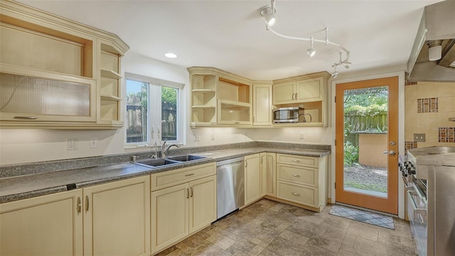 kitchen with track lighting, tasteful backsplash, sink, cream cabinets, and appliances with stainless steel finishes