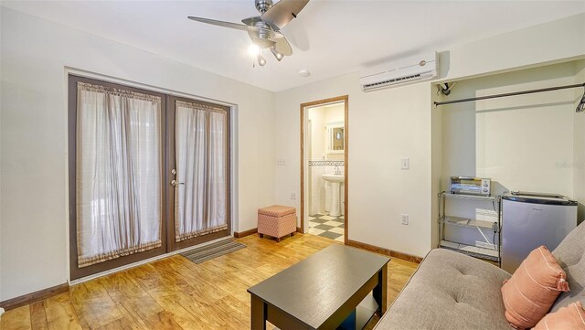 living room featuring a wall unit AC, sink, ceiling fan, and light hardwood / wood-style floors