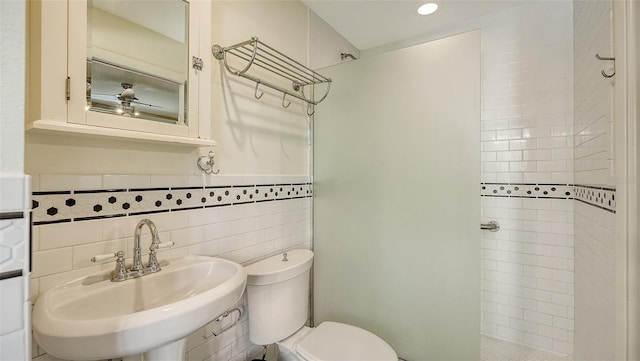 bathroom featuring tile walls, toilet, tiled shower, and sink