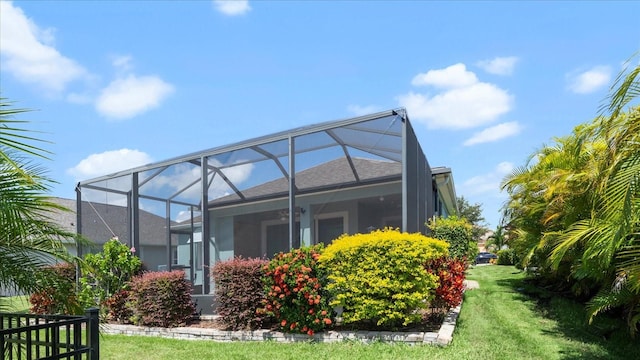 back of property featuring glass enclosure and a yard