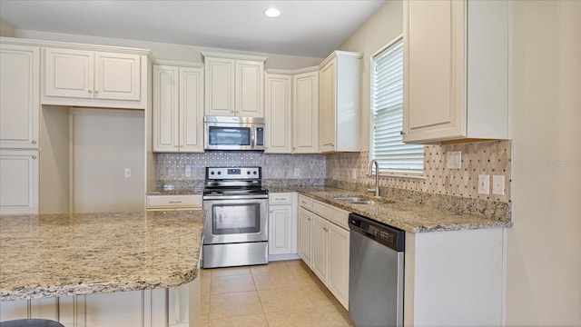 kitchen featuring light stone counters, stainless steel appliances, sink, and backsplash