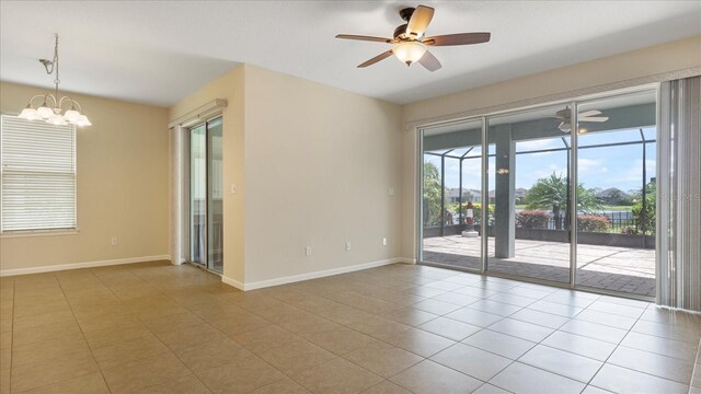 tiled spare room featuring ceiling fan with notable chandelier