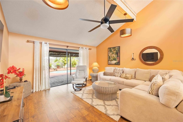 living room with a textured ceiling, ceiling fan, wood-type flooring, and vaulted ceiling