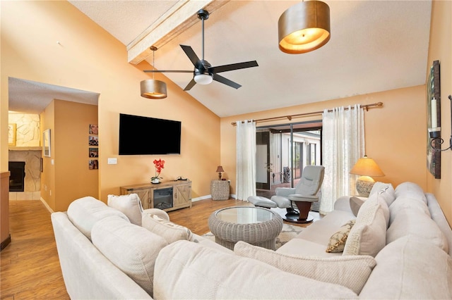 living room featuring ceiling fan, light hardwood / wood-style floors, a textured ceiling, and vaulted ceiling