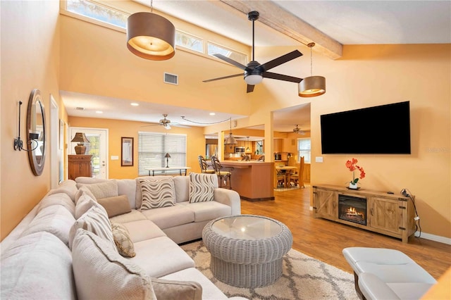 living room featuring light wood-type flooring, ceiling fan, high vaulted ceiling, and beam ceiling