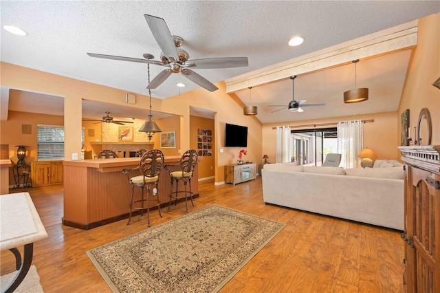 living room featuring a textured ceiling, hardwood / wood-style floors, ceiling fan, and lofted ceiling